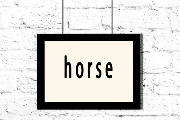 Черная рамка висит на белой кирпичной стене с надписью лошадь — стоковое фото