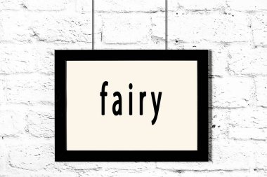 Beyaz tuğla duvarda asılı siyah çerçeve ve yazı perisi