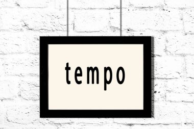 Beyaz tuğla duvarda asılı siyah çerçeve yazı temposuyla