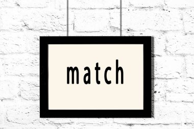 Beyaz tuğla duvarda asılı siyah çerçeve ve yazı eşleşmesi