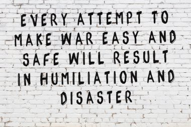 Beyaz tuğla duvar arkaplanına siyah düşünceli bir yazı.