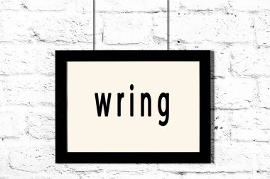 Beyaz tuğla duvarda asılı siyah çerçeve.