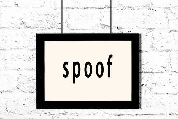 Zwart frame opknoping op witte bakstenen muur met inscriptie spoof — Stockfoto