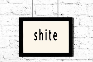 Beyaz tuğla duvarda asılı siyah çerçeve.