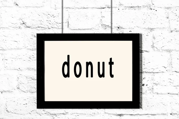 Schwarzer Rahmen an weißer Ziegelwand mit Aufschrift Donut — Stockfoto