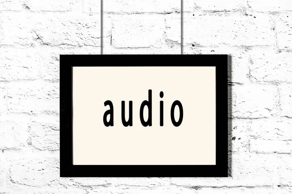 Black frame hanging on white brick wall with inscription audio — Stock Photo, Image