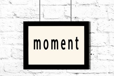 Beyaz tuğla duvarda asılı siyah çerçeve ve yazı anı