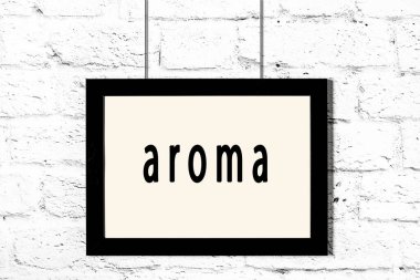 Beyaz tuğla duvarda asılı siyah çerçeve aromalı.
