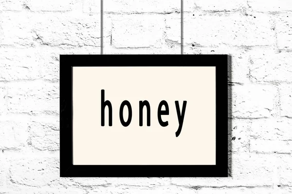 Fekete keret lóg fehér téglafalon felirattal méz — Stock Fotó