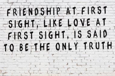 Beyaz tuğla duvara zekice alıntılar yazılı siyah bir yazı.