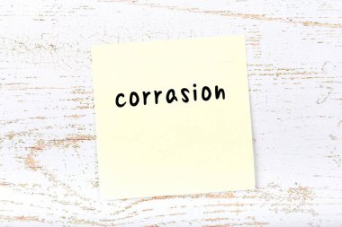 Tahta duvardaki sarı yapışkan notta el yazısıyla yazılmış aşınma izi var.