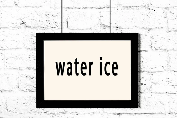 Czarna ramka wisząca na białej ceglanej ścianie z napisem lód wody — Zdjęcie stockowe