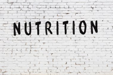 Üzerinde siyah boya yazılı besin olan beyaz bir duvar.