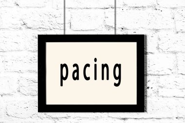 Siyah çerçeve beyaz tuğla duvarda asılı, üzerinde volta var.