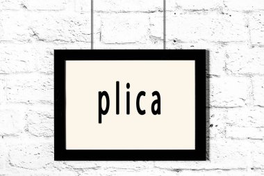 Beyaz tuğla duvarda asılı siyah çerçeve.