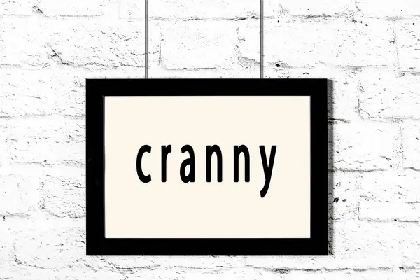 Quadro preto pendurado na parede de tijolo branco com inscrição cranny — Fotografia de Stock