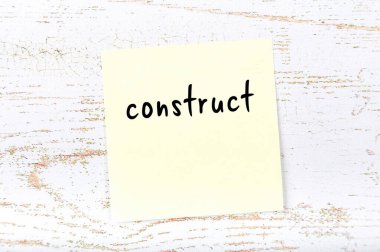 Tahta duvarda el yazısıyla yazılmış sarı yapışkan not.