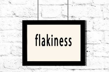 Beyaz tuğla duvarda asılı siyah çerçeve.