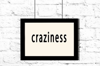 Beyaz tuğla duvarda asılı siyah çerçeve yazı çılgınlığıyla