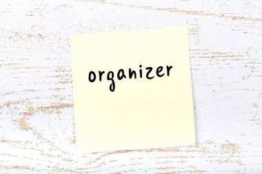 Tahta duvarda el yazısıyla düzenleyici ile sarı yapışkan bir not var.