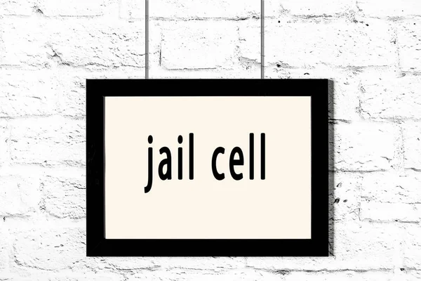 Quadro preto pendurado na parede de tijolo branco com célula de prisão inscrição — Fotografia de Stock