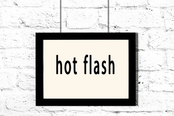 Marco negro colgando en la pared de ladrillo blanco con inscripción hot flash —  Fotos de Stock