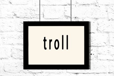 Beyaz tuğla duvarda asılı siyah çerçeve ve yazıt trolü
