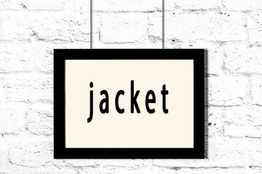 Beyaz tuğla duvarda asılı siyah çerçeve.