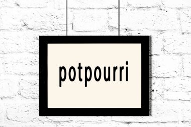 Beyaz tuğla duvarda asılı siyah çerçeve ve yazıt potpurisi