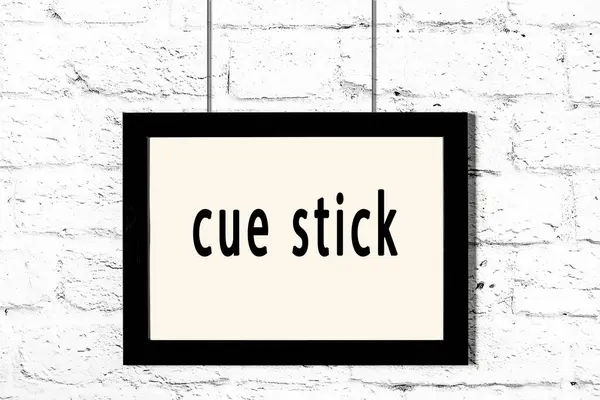 Schwarzer Rahmen an weißer Ziegelwand mit Inschrift Cue-Stick — Stockfoto