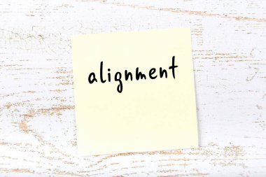 Tahta duvarda el yazısıyla yazılmış sarı yapışkan bir not var.