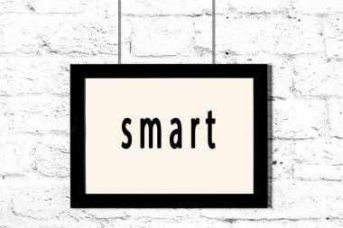 Beyaz tuğla duvarda asılı siyah çerçeve.