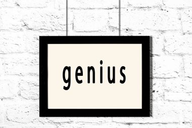 Beyaz tuğla duvarda asılı siyah çerçeve ve yazı dehası.