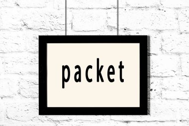 Beyaz tuğla duvarda asılı siyah çerçeve ve yazı paketi