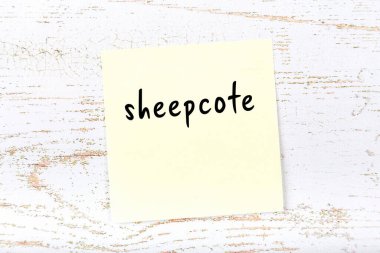 Tahta duvardaki sarı yapışkan notta el yazısıyla yazılmış koyunlar var.