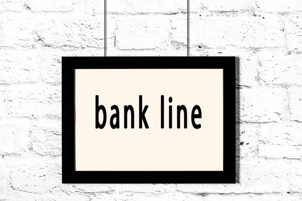 흰 벽돌 벽에 비문 은행 선이 걸려 있는 검은 골조 — 스톡 사진