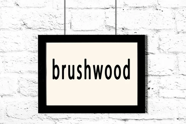 Quadro preto pendurado na parede de tijolo branco com brushwood inscrição — Fotografia de Stock