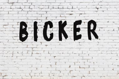 Kelimeler beyaz tuğla duvara kazınmış.