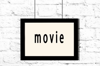 Beyaz tuğla duvarda asılı siyah çerçeve ve yazı filmi