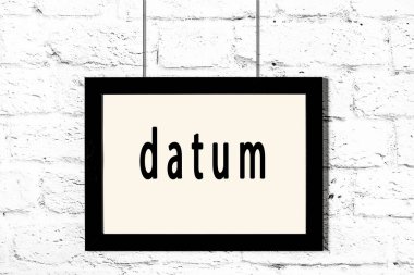 Beyaz tuğla duvarda asılı siyah çerçeve ve yazıt verisi