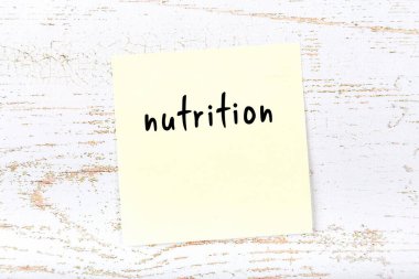 Tahta duvardaki sarı yapışkan notta elle yazılmış besin maddesi var.