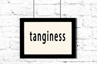 Beyaz tuğladan duvara asılmış siyah çerçeve.