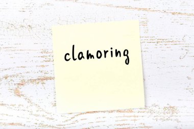 Tahta duvarda sarı yapışkan bir not ve el yazısı yaygara koparıyor.