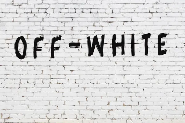 Palavra off-white pintado na parede de tijolo branco — Fotografia de Stock