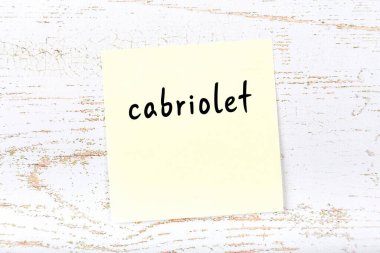 Tahta duvarda el yazısı Cabriolet olan sarı yapışkan bir not.