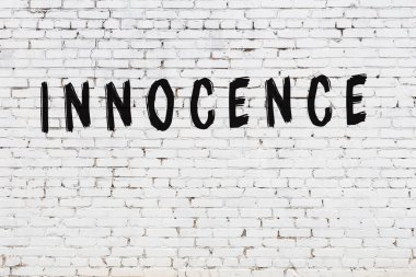 Beyaz tuğla duvara yazılmış kelime masumiyeti.