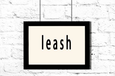 Beyaz tuğla duvarda asılı siyah çerçeve ve yazı tasması