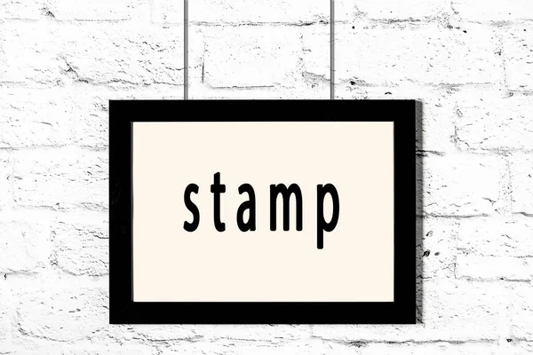 碑文の切手と白いレンガの壁にかかっている黒いフレーム — ストック写真