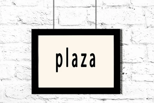 Schwarzer Rahmen hängt an weißer Ziegelwand mit Inschrift Plaza — Stockfoto