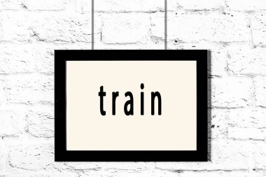 Beyaz tuğla duvarda asılı siyah çerçeve ve yazı treni